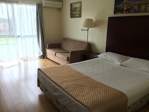 A hotel room with a bed, a sofa, a lamp, and a painting on the wall. - Centenary Motor Inn (Darra)