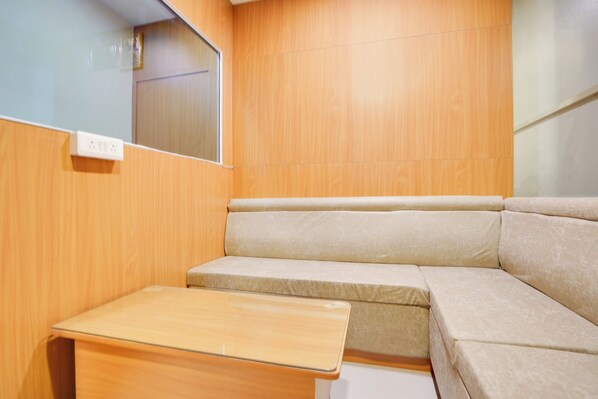 Quarto compacto e moderno, com parede de painel de madeira, um banco estofado e uma pequena mesa de madeira.