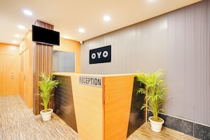 Ein Empfangsschalter mit einem Schild, das 'OYO' und 'REZEPTION' zeigt, in der Hotelhalle.