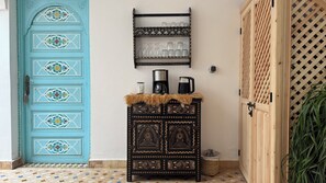 A blue door with intricate patterns, a black cabinet with a fur throw, a coffee maker, and a wooden door with a lattice design. - Dar 82, votre Riad privé dans la Kasbah, 4 chambres et petit-déjeuner inclus (Marrakesh)