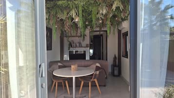 An open-plan living space with a dining area, a sofa, and hanging plants.