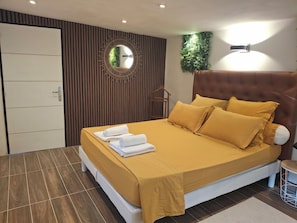 A modern bedroom with a large bed, a mirror, a wall-mounted light, and a door with a handle. - New Listing (Vergèze)