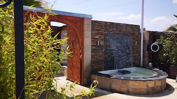 A spa area with a hot tub, a wooden door, and a brick wall.