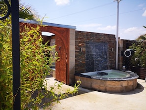 A spa area with a hot tub, a wooden door, and a brick wall. - New Listing (Vergèze)