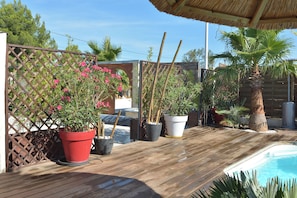 Une terrasse en bois agrémentée de plantes en pot et d’une piscine.