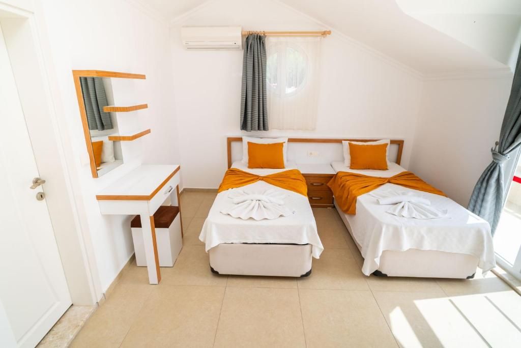 A room with two beds, a desk, and a window with curtains.