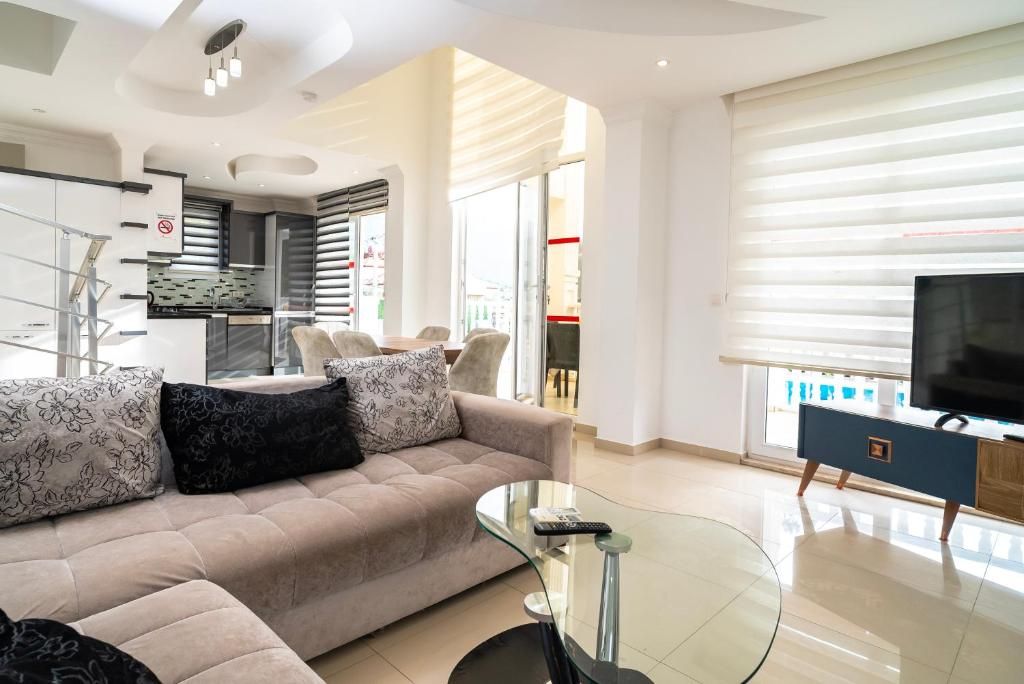 A modern living room with a sofa, a glass coffee table, and a television.