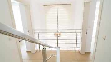 A corridor with a metal handrail, a basketball hoop, and a door on the right.