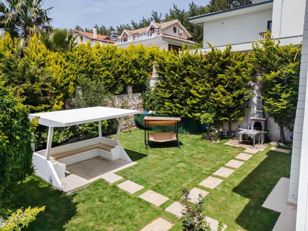 A backyard with a patio, a barbecue grill, and a small garden area.