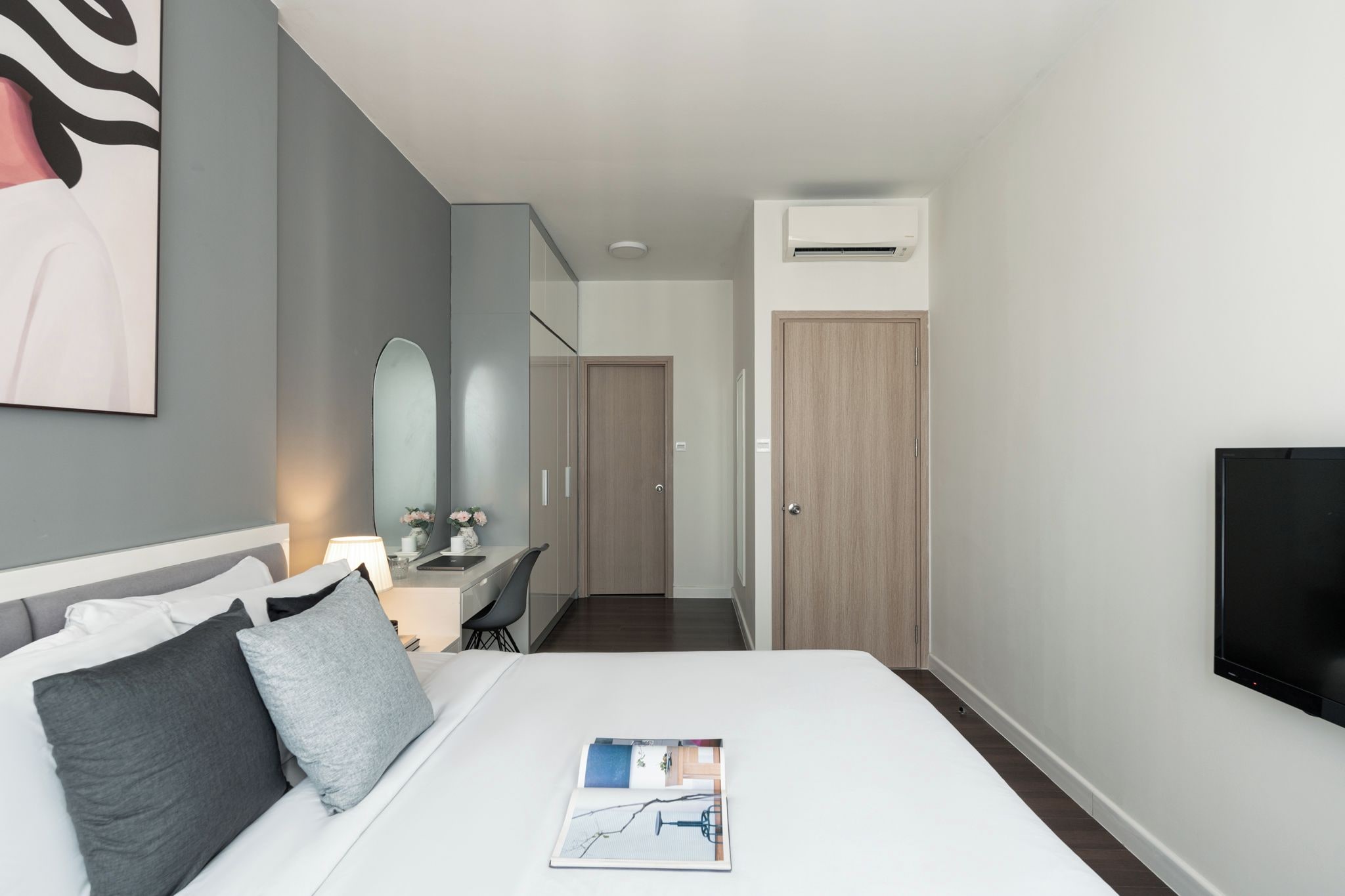 Una camera d'albergo con un letto, una scrivania, una sedia, una televisione e una porta.