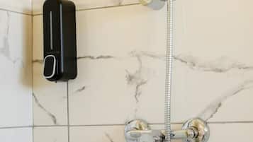 A bathroom with a shower, a handheld showerhead, and a soap dispenser.