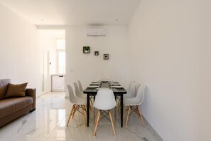 Un comedor moderno con una mesa rectangular, sillas blancas y un sofá marrón.