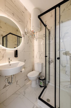A modern bathroom with a glass-enclosed shower, a sink with a mirror, and a toilet. - RODOLFU F8 (Tas-Sliema)
