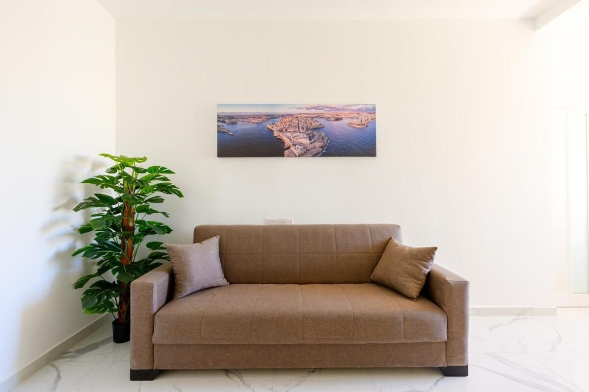 Un salon avec un canapé, une plante en pot et un tableau accroché au mur.