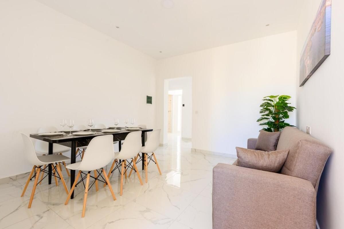 A dining area with a table set for four, surrounded by chairs with wooden legs.