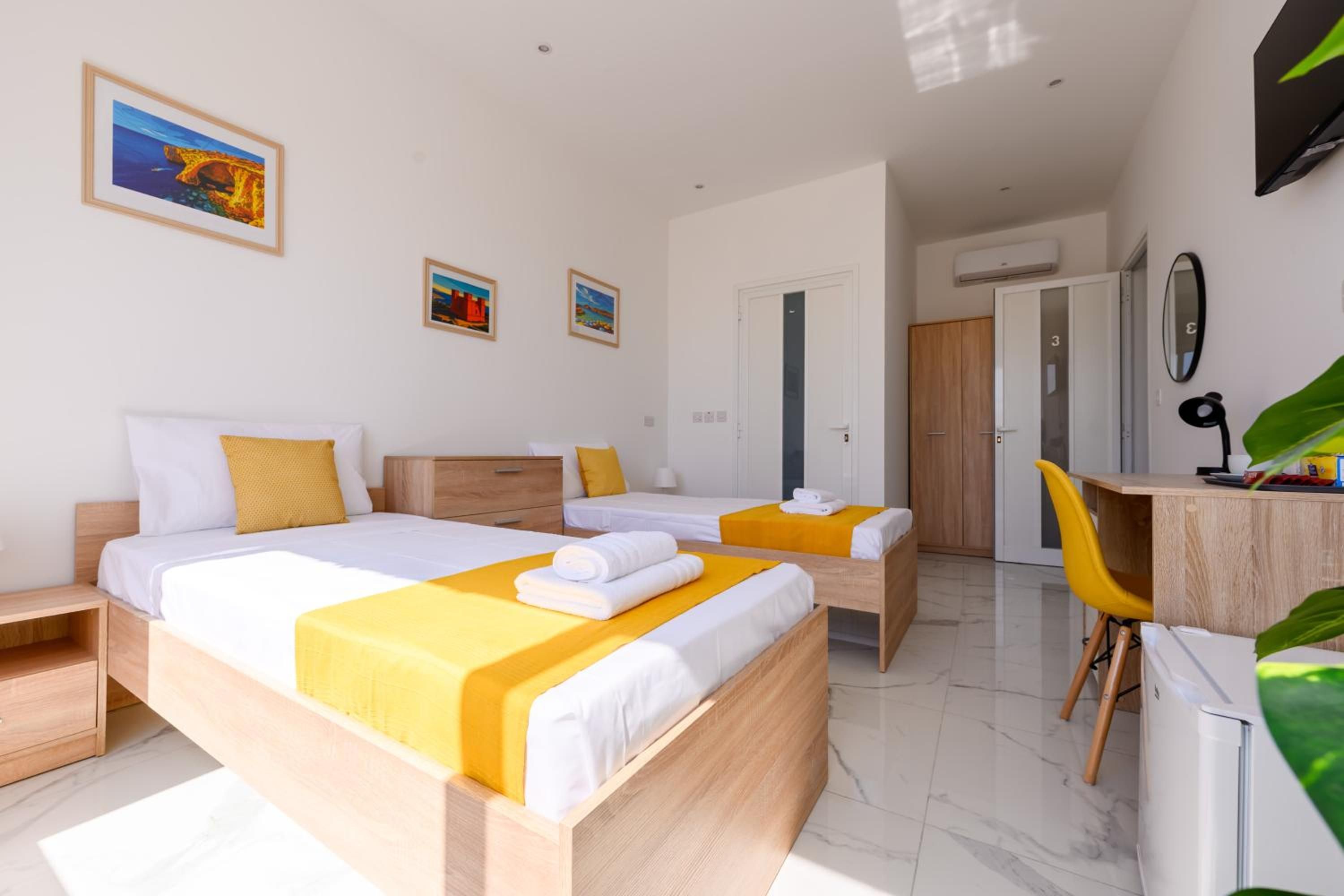 A hotel room with two beds, a desk, and a chair.