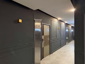 Um corredor com portas, cada uma delas identificada com um número, dando acesso a quartos individuais.