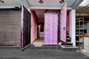 A hallway with a closed door, a staircase, and a patterned door. - Hotel O Moonville Pusta (Noida)
