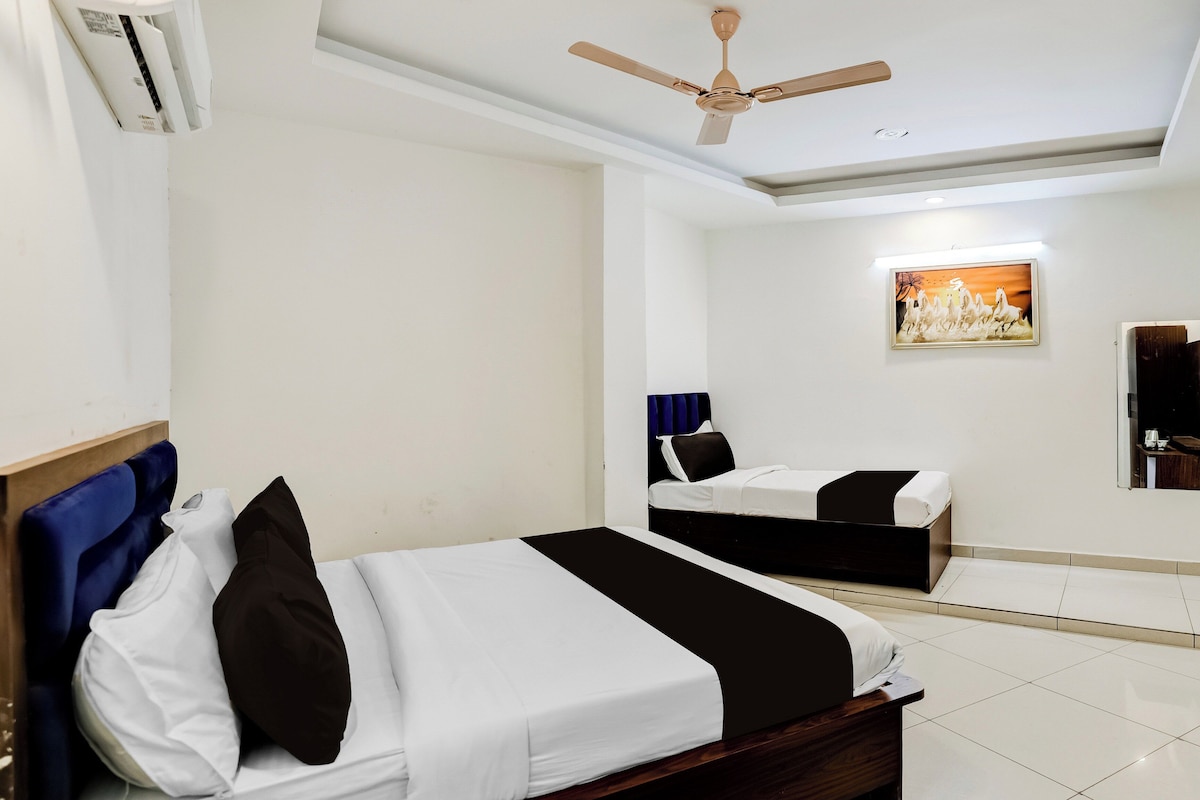 A hotel room with two beds, a ceiling fan, a painting on the wall, and a tiled floor.