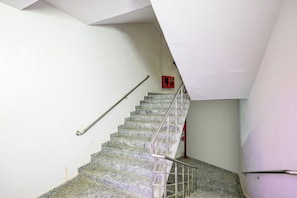 A staircase with a metal handrail and a red emergency exit sign on the wall.