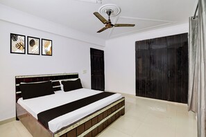 Une chambre à coucher avec un lit, un ventilateur de plafond, une porte et une armoire.