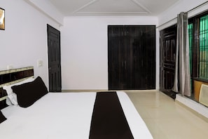 Une chambre d’hôtel avec un lit, une porte et une fenêtre avec des rideaux.