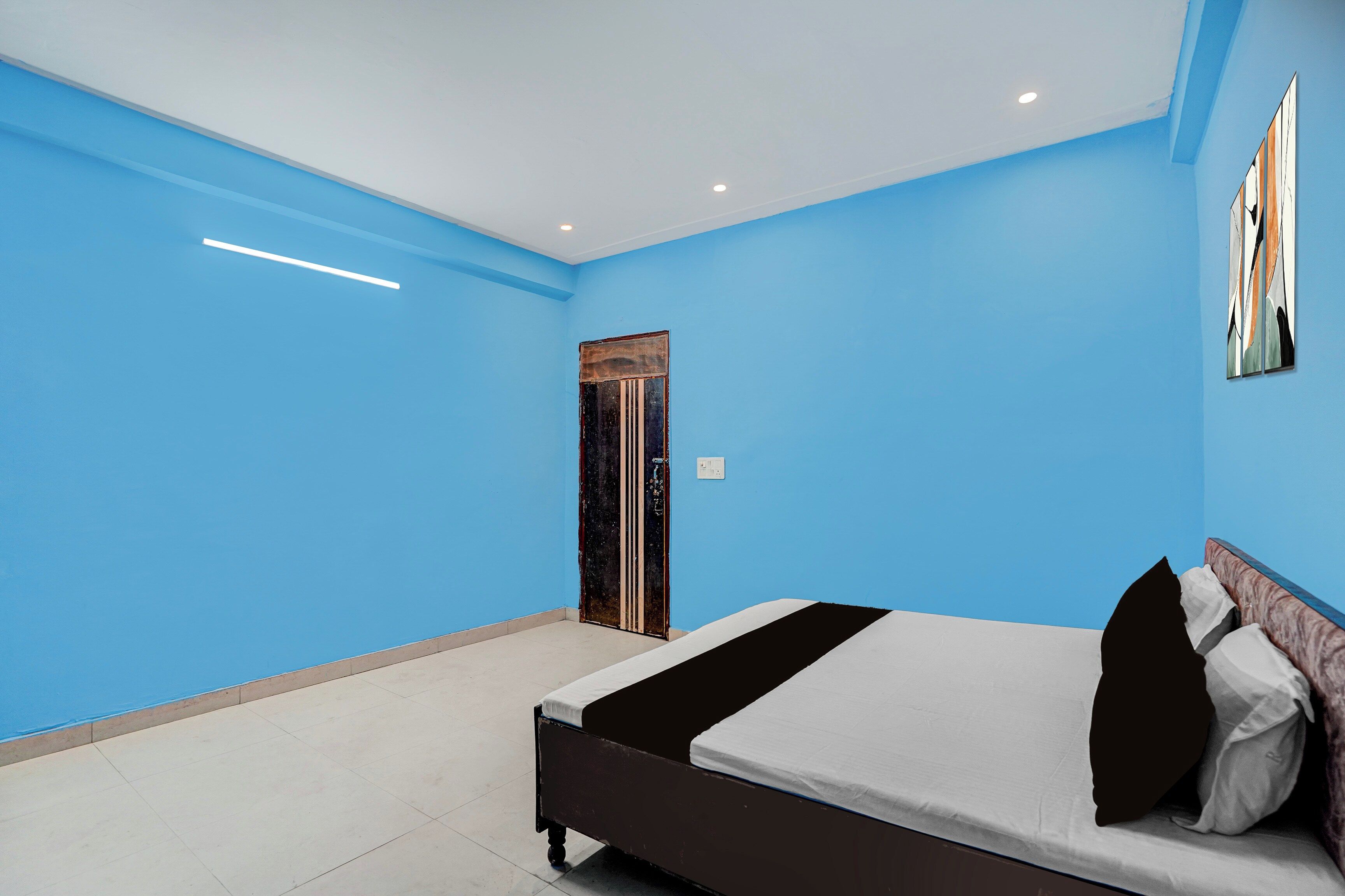 Un dormitorio con cama, una puerta y una pared con un cuadro.