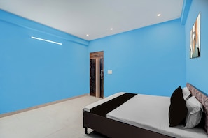 Un dormitorio con cama, una puerta y una pared con un cuadro.