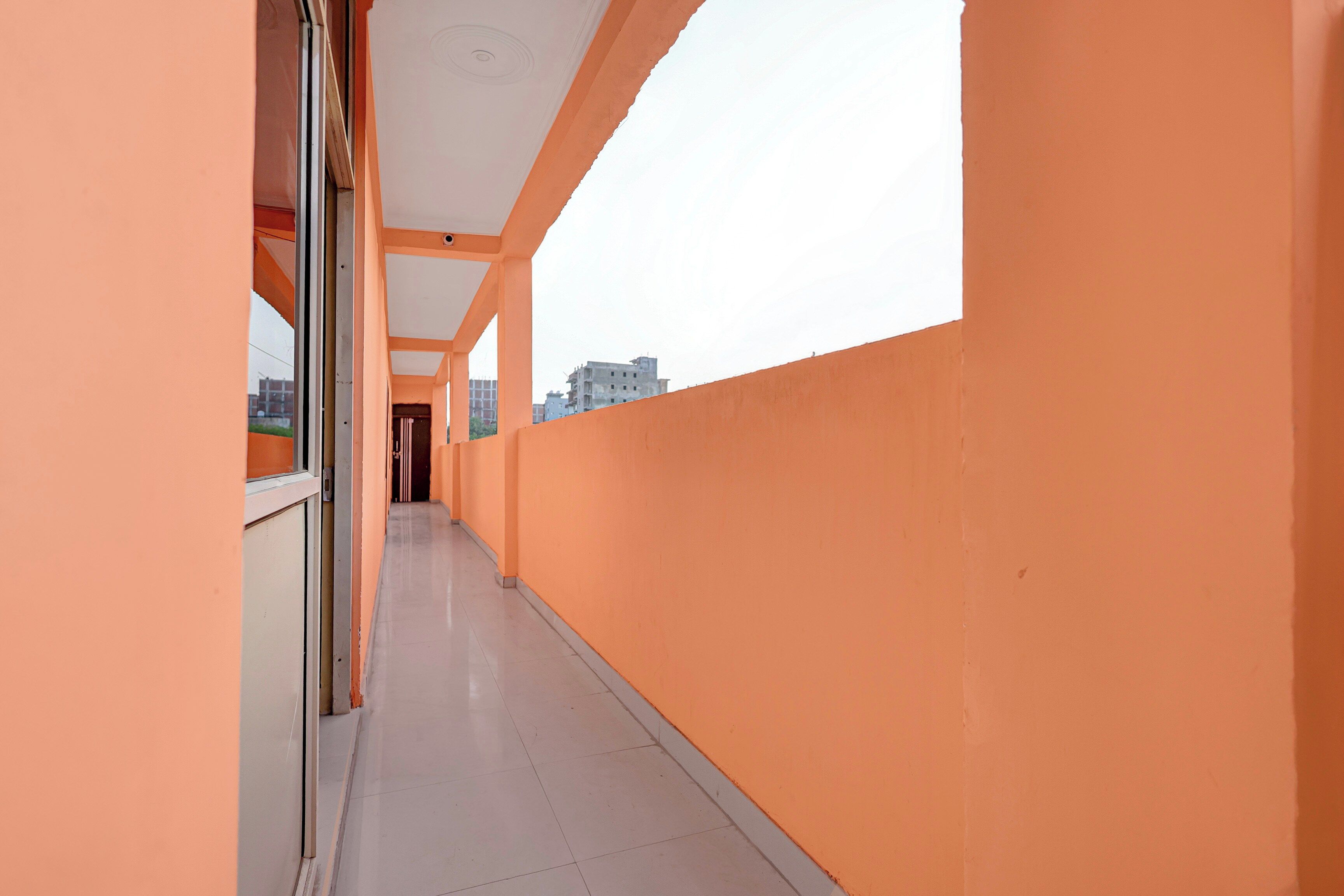 A corridor with orange walls and a tiled floor, leading to a door at the end.