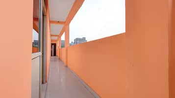 A corridor with orange walls and a tiled floor, leading to a door at the end.