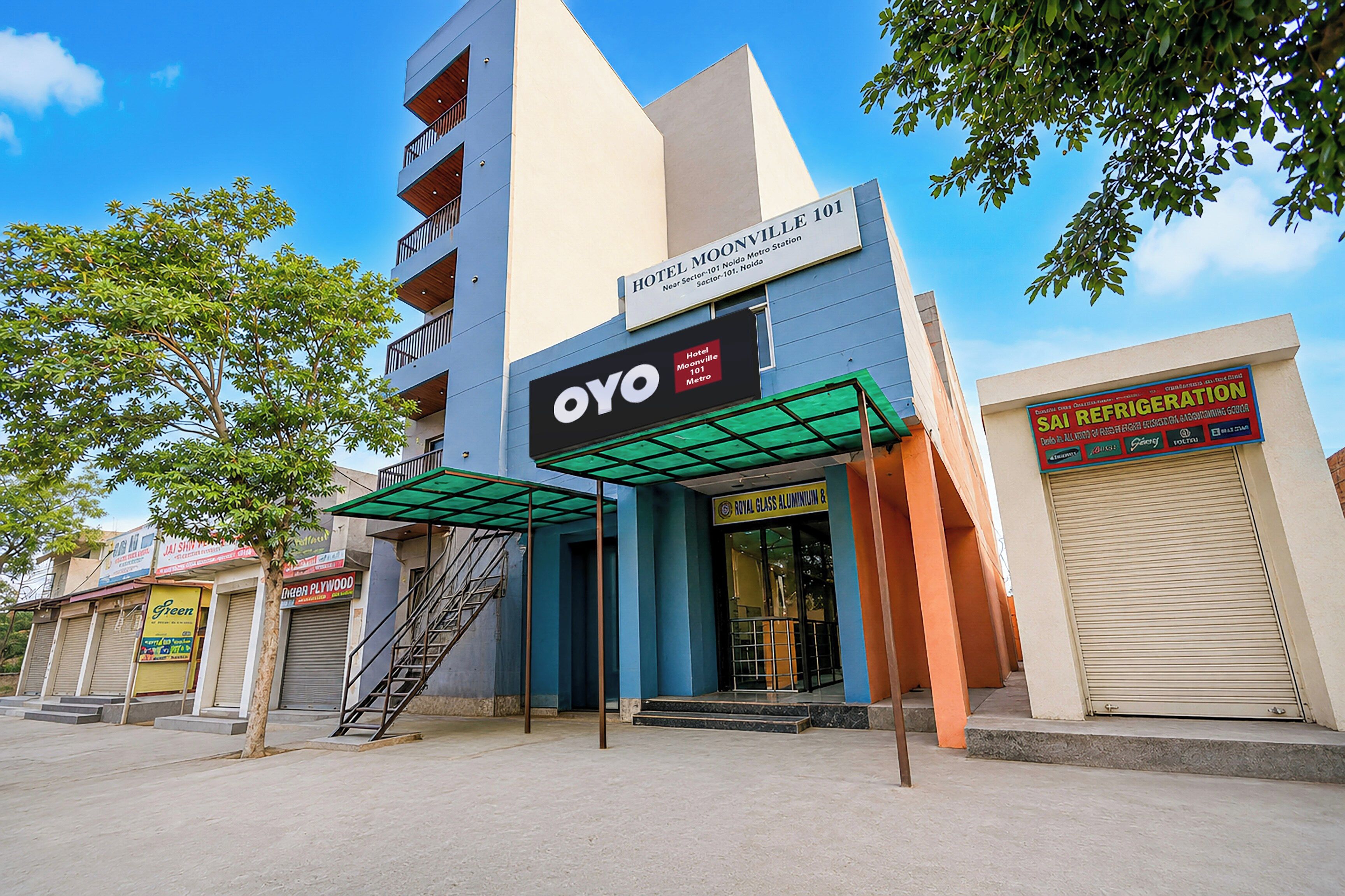 Een hotel met een modern design, een bord met Hotel Moonville 101 Metro en een gevel van Royal Glass Aluminum & SAI Refrigeration.