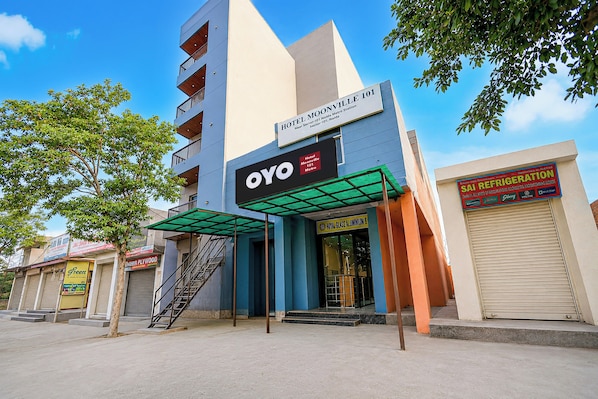Un hôtel au design moderne, une enseigne indiquant « Hôtel Moonville 101 Metro », et une vitrine pour les entreprises Royal Glass Aluminum et SAI Refrigeration.