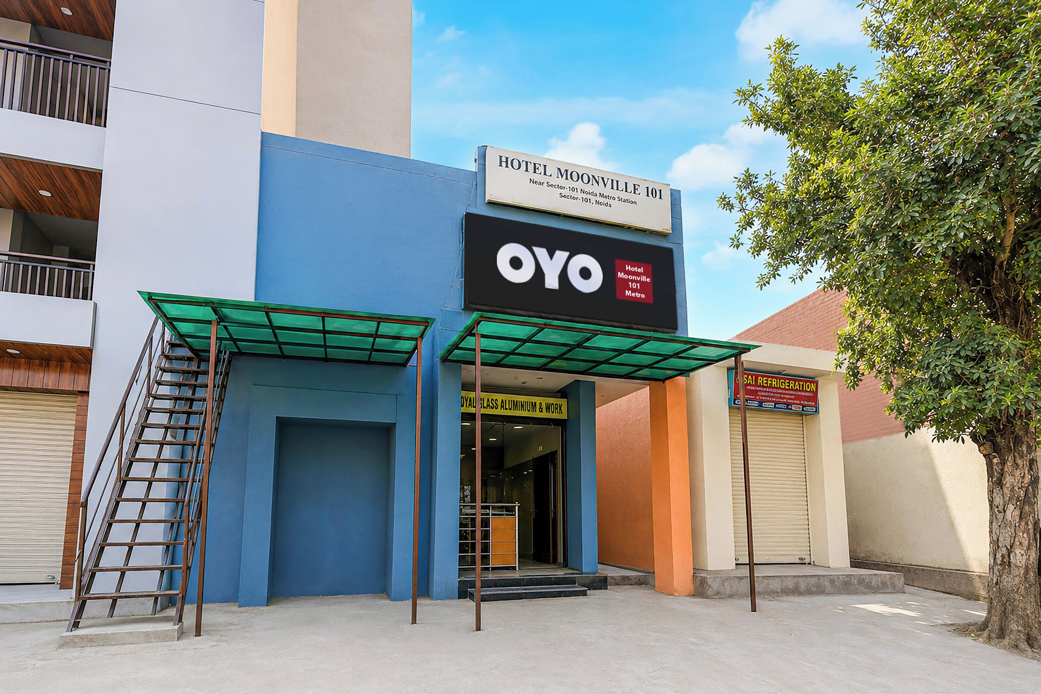 A hotel with a blue facade, a sign for OYO, and a visible entrance.
