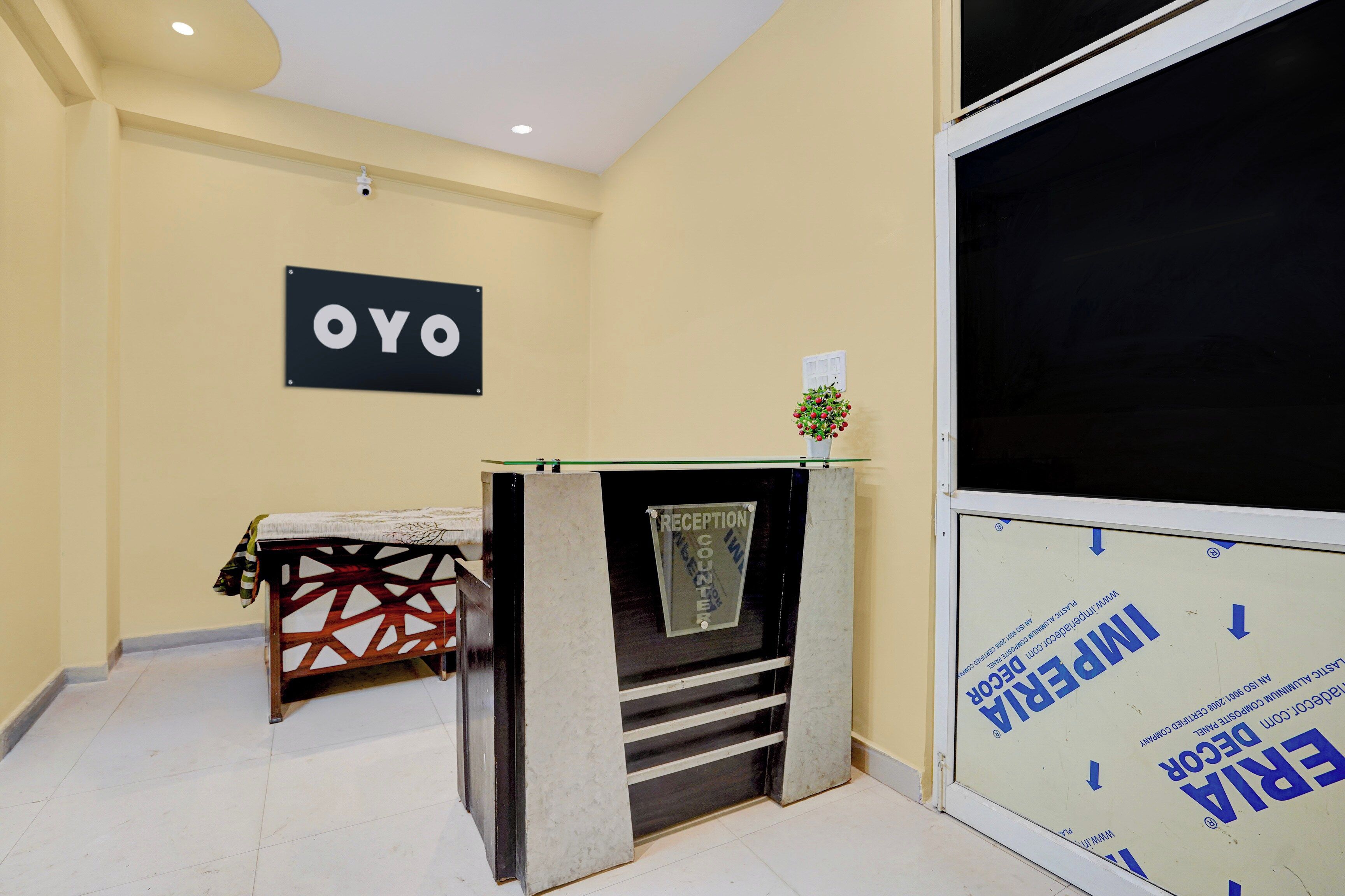 Een receptie met een receptiebalie, een bord aan de muur met de tekst 'OYO' en een raam met uitzicht op buiten.