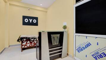 Een receptie met een receptiebalie, een bord aan de muur met de tekst 'OYO' en een raam met uitzicht op buiten.