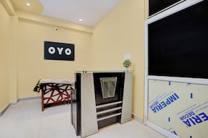 Un espace d'accueil comprenant un comptoir de réception, une enseigne murale indiquant « OYO », et une fenêtre donnant sur l’extérieur.
