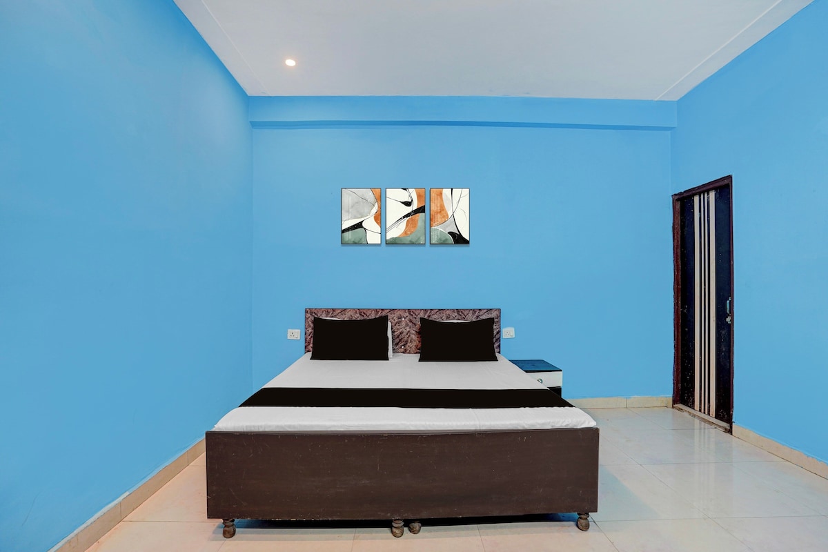 Un dormitorio con cama, mesita de noche, una obra de arte en la pared y una puerta.