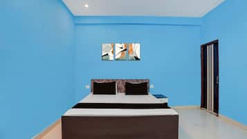 Une chambre à coucher comprenant un lit, une table de chevet, une œuvre d’art accrochée au mur et une porte.