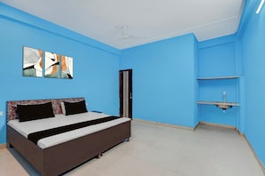 Une chambre à coucher avec un lit, des œuvres d’art accrochées au mur, un ventilateur de plafond et un lavabo.