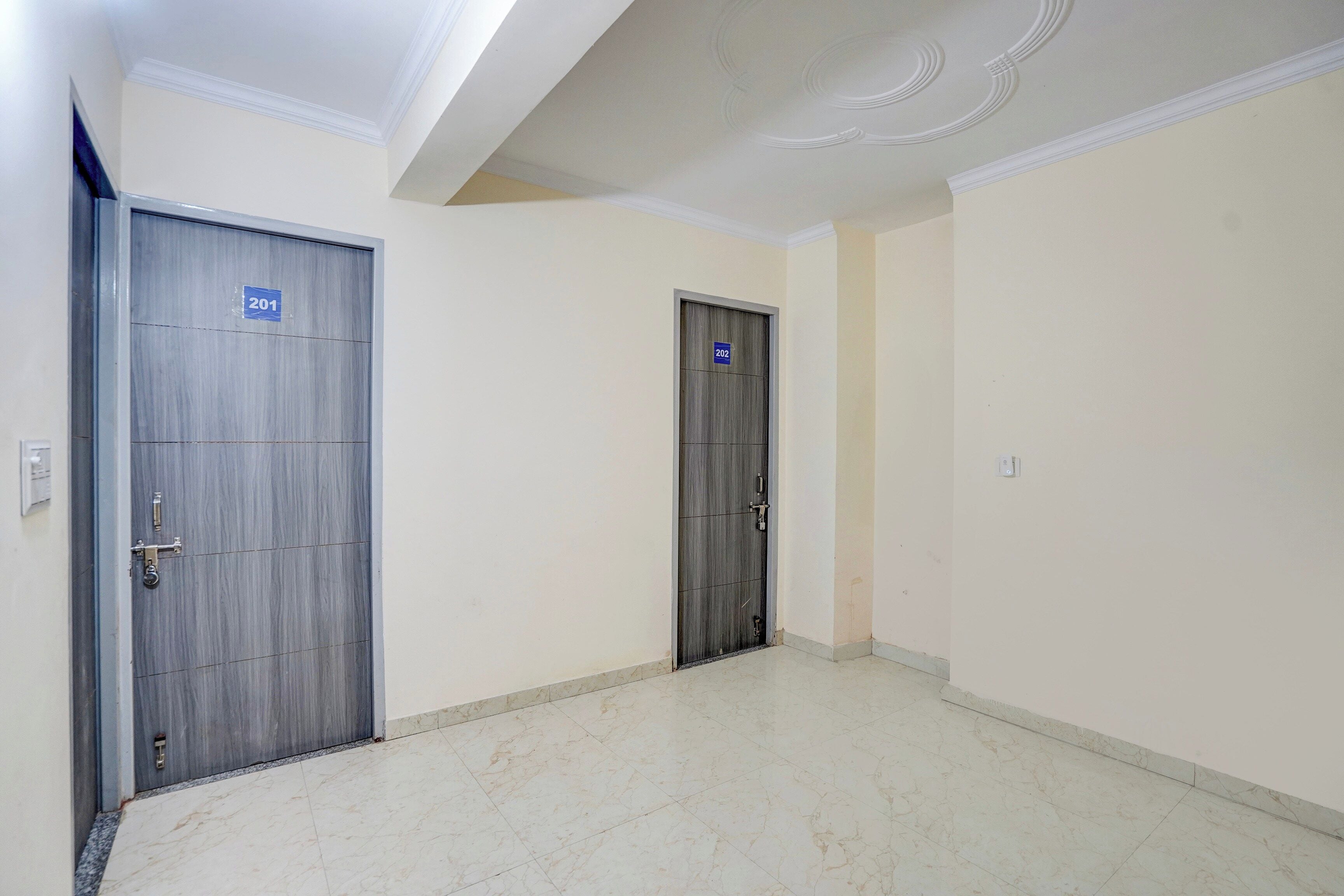 A hallway with two doors, each marked with a number. The floor is tiled, and the walls are plain.