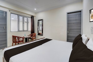 Ein Hotelzimmer mit Bett, Schreibtisch, Stuhl, Fenster und Tür.