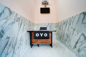 A reception desk with a sign reading 'OYO' in a modern lobby with marble walls and a wooden base. - Hotel O Diamond Hotel (Noida)