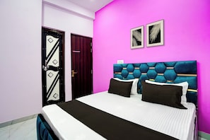 Un dormitorio con una cama, una puerta y dos cuadros en la pared.