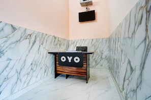 Una mesa de recepción con un fondo de pared de mármol y un cartel que dice 'OYO'.