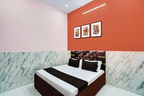 Un dormitorio con una cama, cabecero y una pared decorada con tres obras enmarcadas.