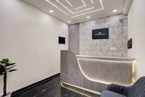 A reception desk with a marble-patterned wall, a sign reading 'OYO TOWNHOUSE', and a modern, illuminated reception area. - Townhouse Rosens hotel (Noida)