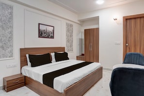 A bedroom with a wooden bed, bedside tables, a wardrobe, and a chair. - Townhouse Rosens hotel (Noida)
