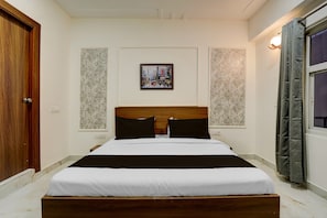 A hotel room with a wooden bed, white bedding, a framed cityscape picture on the wall, and a window with curtains. - Townhouse Rosens hotel (Noida)