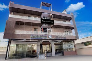 Um edifício de vários andares com uma placa indicando 'OYO TOWNHOUSE' e 'MEENAKSHI DIAGNOSTICS' no andar térreo.
