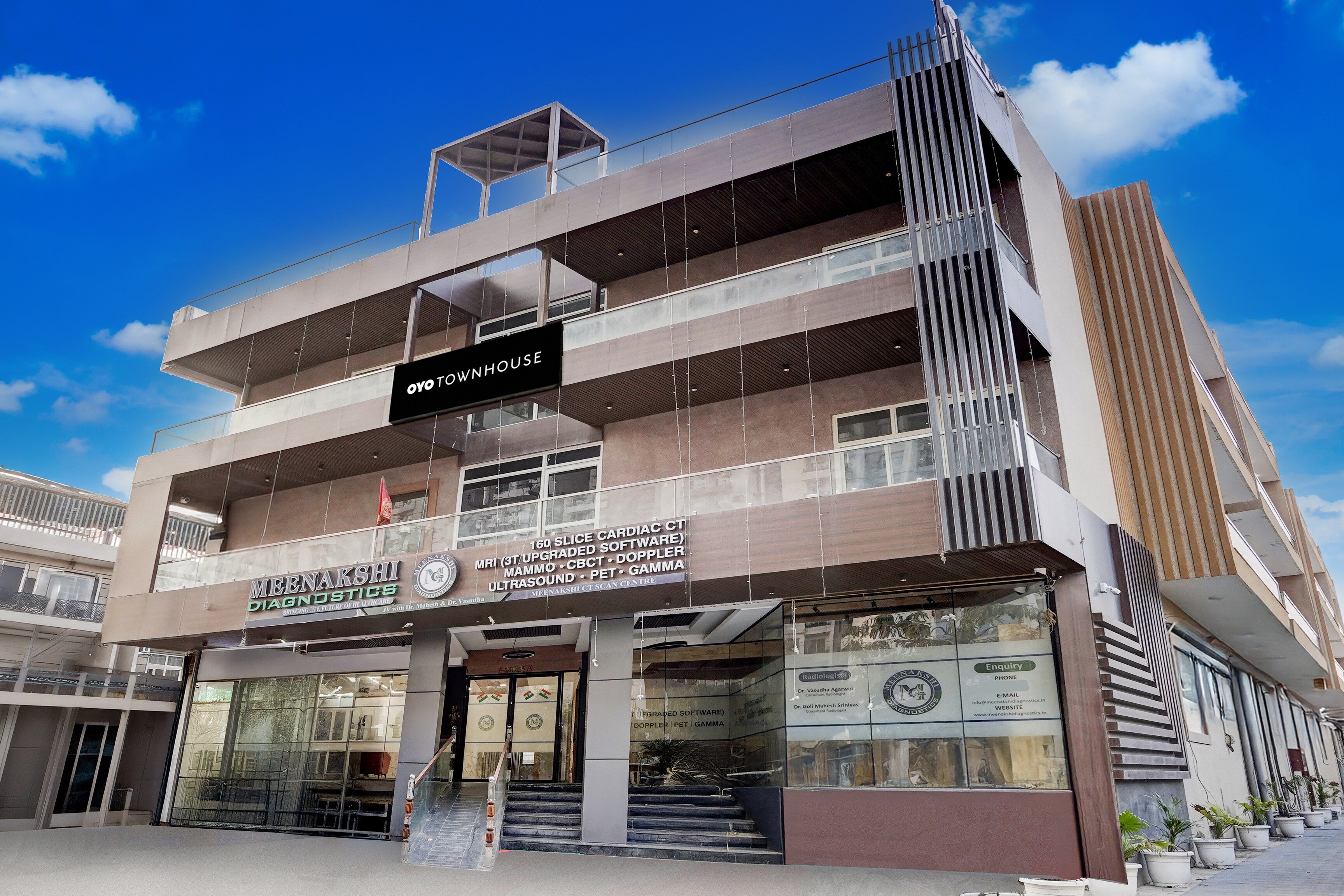 A multi-story building with a sign for 'Oyo Townhouse' and 'Meenakshi Diagnostics' indicating a medical facility.